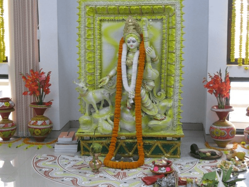 Yellow flowers and fruits arranged respectfully for Saraswati worship