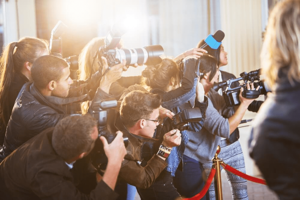 Photographers crowding a celebrity, highlighting how fame becomes media focus
